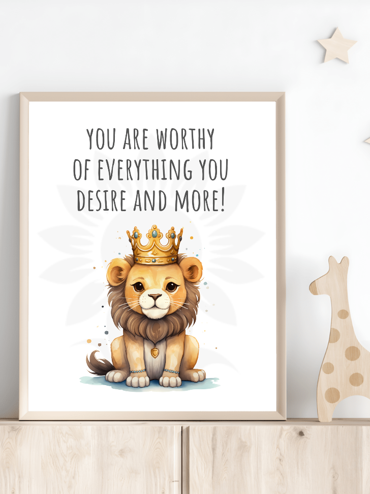 Nursery room decor with framed wall art of a majestic lion with a crown and the text 'YOU ARE WORTHY OF EVERYTHING YOU DESIRE AND MORE!' The design, from Blossoming Minds, is displayed on a shelf next to a wooden giraffe toy, encouraging positive affirmations for children.